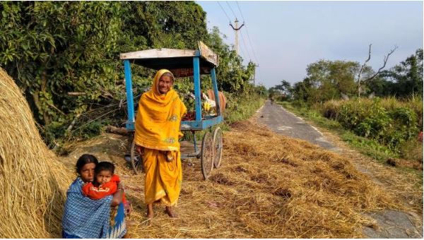 Seema [left, with her child] and Sakiya basking in the sun while the hay, used as cattle seat in the night, spread on the road to dry. One of the handcarts stands behind Sakiya..JPG